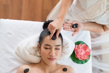 Obraz na płótnie Canvas Young beautiful Asian woman relaxing having facial massage with mineral stone in the spa