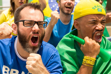 Goal, victory, celebration. Friends from Brazil watching football match.