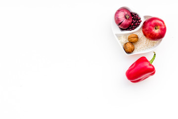 Diet for healthy heart. Food with antioxidants. Vegetables, fruits, nuts in heart shaped bowl on white background top view copy space