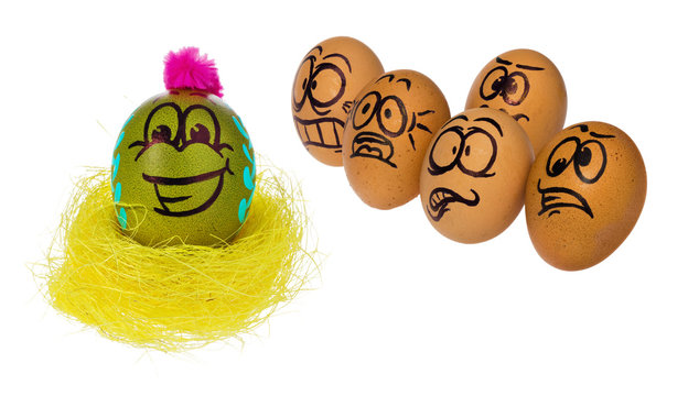Eggs in natural colors look with horror, astonishment and fear at colored smiling face of Easter eggs in a bird's nest.