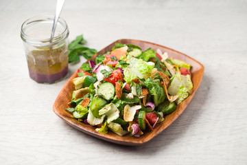 Fattoush salad plate and dressing. The key ingredient in this middle eastern dish is the toasted pita bread which is mixed with healthy vegetables, herbs and a dressing made with lemon and sumac.
