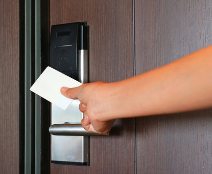 Young woman holding a key card to unlock door.