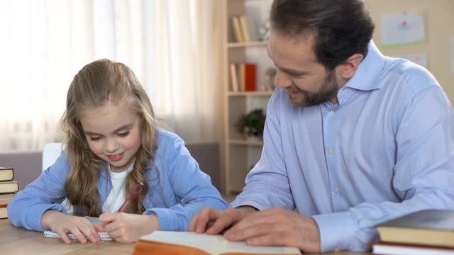 Proud father doing homework together with his daughter, education, family care