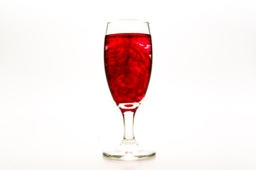 Red food coloring diffuse in water inside wine glass with empty copy-space area for slogan or advertising text message, over isolated white background.