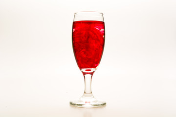 Red food coloring diffuse in water inside wine glass with empty copy-space area for slogan or advertising text message, over isolated white background.