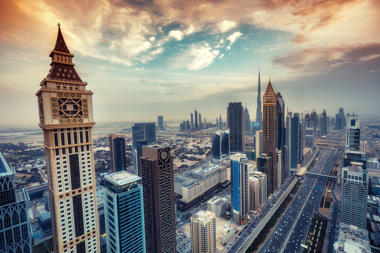 Aerial view on skyscrapers of Dubai, UAE, at sunset. Scenic cityscape with dramatic clouds. Toned travel and architectural background.
