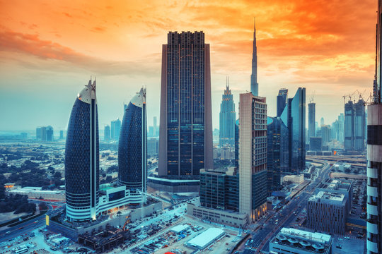 Scenic skyline of big modern city with world famous skyscrapers. Aerial perspective of downtown Dubai, UAE at sunset. Multicolored travel background.