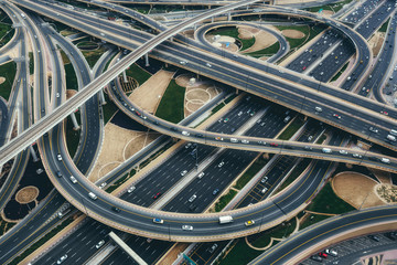 Fototapeta premium Widok z lotu ptaka na duże skrzyżowanie autostrad z ruchem w Dubaju, ZEA, w dzień. Malowniczy pejzaż. Kolorowe tło transportu, komunikacji i jazdy.