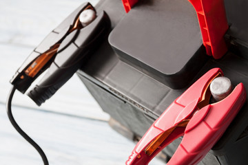 A car battery with red and black battery jumper clamps. Closeup, selective focus