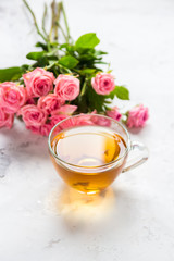 Cup of tea and tender pink roses on a white background