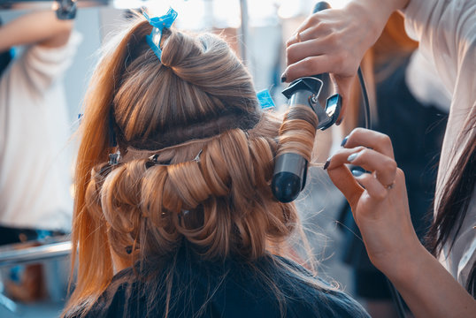 The hairdresser does hair extensions to a young girl