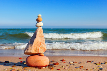 Pyramid of multicolored pebbles on a background of the summer sea.