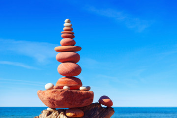 Pyramid of red pebbles on a background of the summer sea.