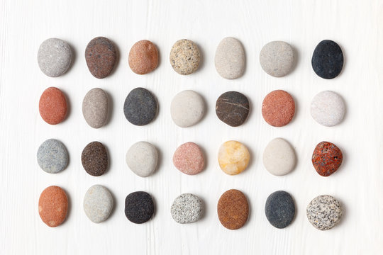 Pattern of natural multicolored pebbles on white wooden background.
