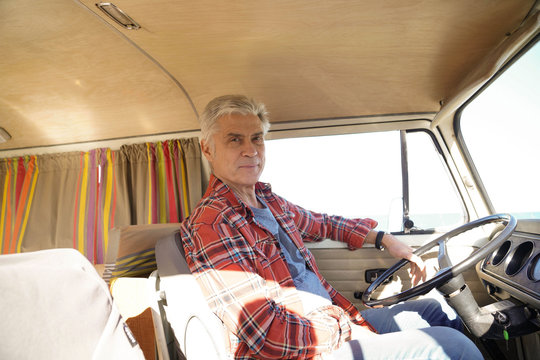 Senior man sitting at camper van steering wheel
