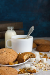 Oatmeal cookies, Books, Oatmeal Flakes, Cup of Coffee with Milk, Raisins on a light background. The concept of Good Morning and Breakfast