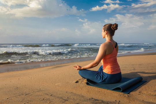 Woman doing yoga Lotus pose oudoors at beach