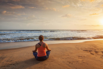 Fototapeta na wymiar Woman doing yoga Lotus pose oudoors at beach