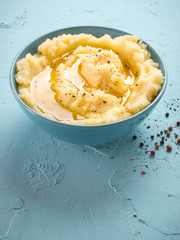 Mashed potatoes with peppers and olive oil in blue bowl on blue concrete background. Vertical.