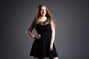 Happy plus size fashion model, sexy fat woman on gray studio background, overweight female body