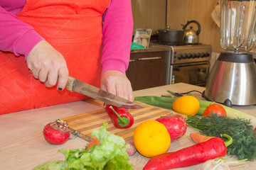 Woman's hands cutting pepper, behind fresh vegetables. Woman cook at the kitchen. Chef cuts the vegetables into a meal