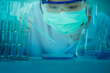 Asian women scientist with test tube making research in clinical laboratory.Science, chemistry, technology, biology and people concept