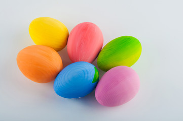 Group of six colored wooden eggs on white background