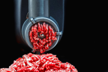 Mincer makes raw meat minced. Black background. Vertical photo. Place for copyspace. Front view.