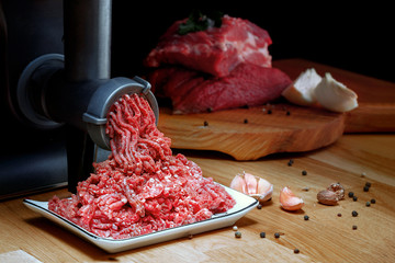 Minced meat coming out from grinder. Healthy homemade minced meat. Dark background. Horizontal view...
