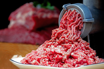 Minced meat coming out from grinder. Healthy homemade minced meat. Dark background. Horizontal view...