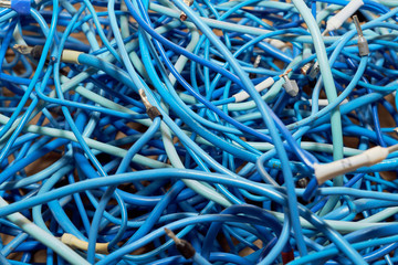 Tangled lump or pile of blue electrical patch cords. The disorder and chaos from the wastes or scraps of tangled cables in a bundle or ball. Entanglement, confusion. Abstract background.