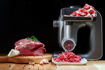 Mincer electric with fresh minced meat. Black background. Horizontal view photo. Place for...