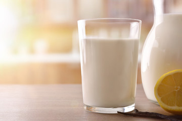 Glass of milk on wooden table lemon and cinnamon front