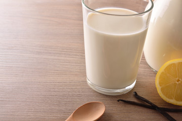 Glass of milk on wooden table lemons and cinnamon closeup