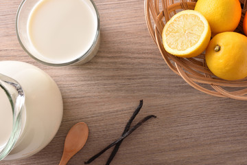Obraz na płótnie Canvas Glass of milk on wooden table lemons and cinnamon top