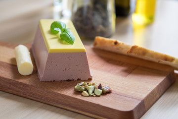 Entenleber Paté mit Champagnergelee auf Holzbrett in Küche mit Pistazien