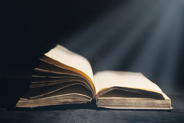 Old book opened  and light on dark bg photo