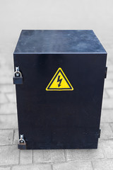 Metal safe box with two padlocks and yellow electricity danger sign on pavement floor, with clipping path. 