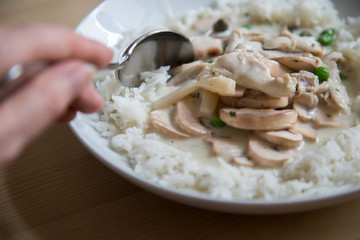 Frau isst mit Löffel traditionelles Hühnerfrikassee mit Reis