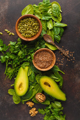 Green salad. Vegan ingredients: spinach, avocado, flax and pumpkin seed. Food background. Detox vegan healthy food concept. Top view, copy space.