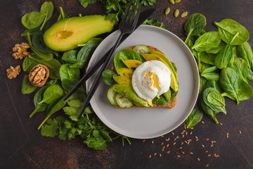 Fresh avocado breakfast with egg poached sandwich. Green salad and seeds, healthy vegetarian food concept. Food background. Top view, copy space.
