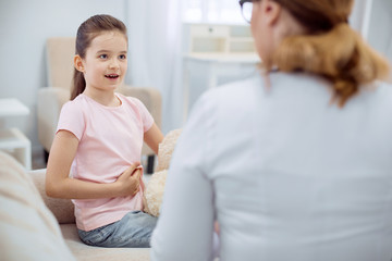 Where pain. Energetic positive girl describing symptoms and showing pain area while female doctor listening to her