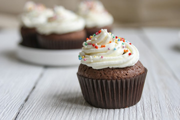 Chocolate cupcake with white cream and colorful decorations