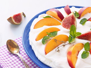 Traditional Pavlova dessert decorated with figs and other summer fruits. Selective focus.
