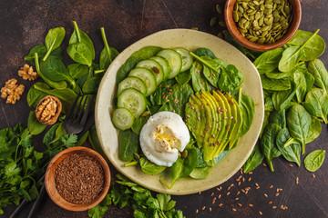 Green salad with spinach, cucumber, avocado, egg, flax and pumpkin seed. Food background. Detox Vegetarian Healthy Food Concept. Top view, copy space.