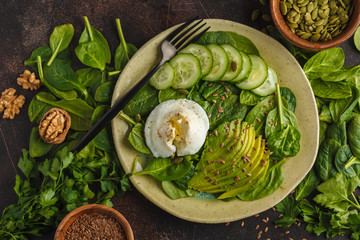Green salad with spinach, cucumber, avocado, egg, flax and pumpkin seed. Food background. Detox Vegetarian Healthy Food Concept. Top view, copy space.