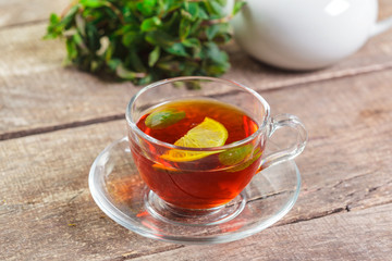 cup of black tea with mint leaves on a wooden table