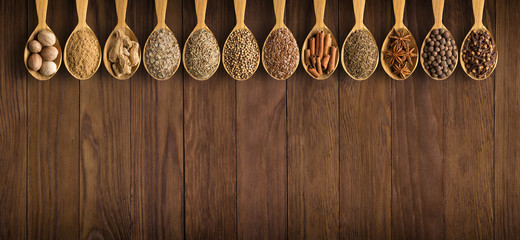 collection of Indian spices and herbs on  background  wooden table. Seasoning in spoons, top view