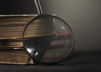 Three old book with glass on wooden bg