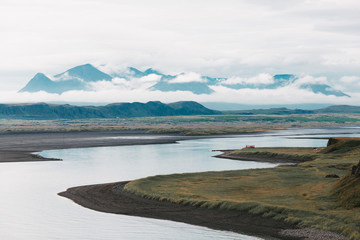beautiful landscape with wide river and mountain peaks in clouds, iceland